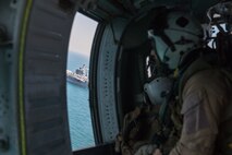 Naval Aircrewman (Helicopter) 2nd Class Steve Reynolds, assigned to Helicopter Sea Combat Squadron (HSC) 26, watches from an MH-60S Sea Hawk helicopter as the aircraft carrier USS Nimitz (CVN 68) sails in the Arabian Gulf, Oct. 11. HSC-26 and the Nimitz Carrier Strike Group are deployed to the U.S. 5th Fleet area of operations in support of naval operations to ensure maritime stability and security in the Central Region, connecting the Mediterranean and Pacific through the Western Indian Ocean and three critical chokepoints to the free flow of global commerce.