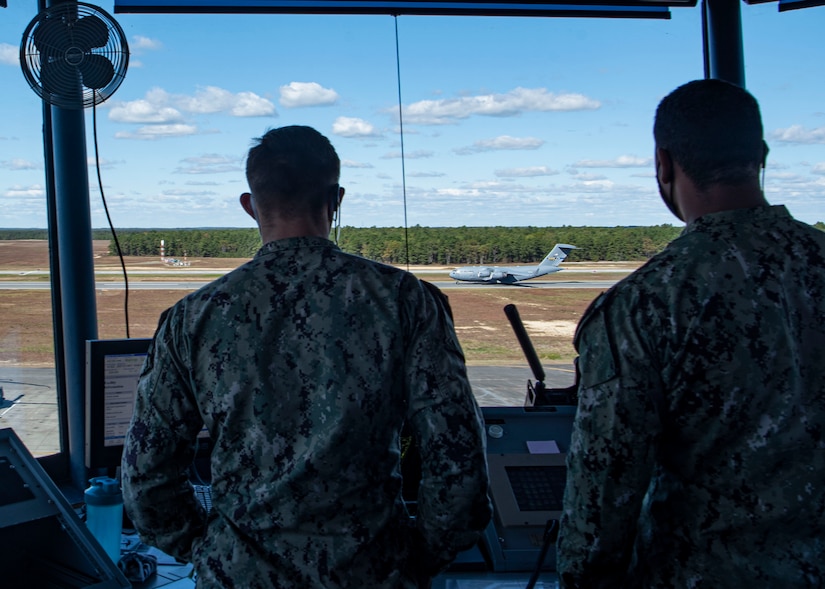 Photo of sailors assigned to the 305th Operations Support Squadron watching a C-17 Globemaster III land.