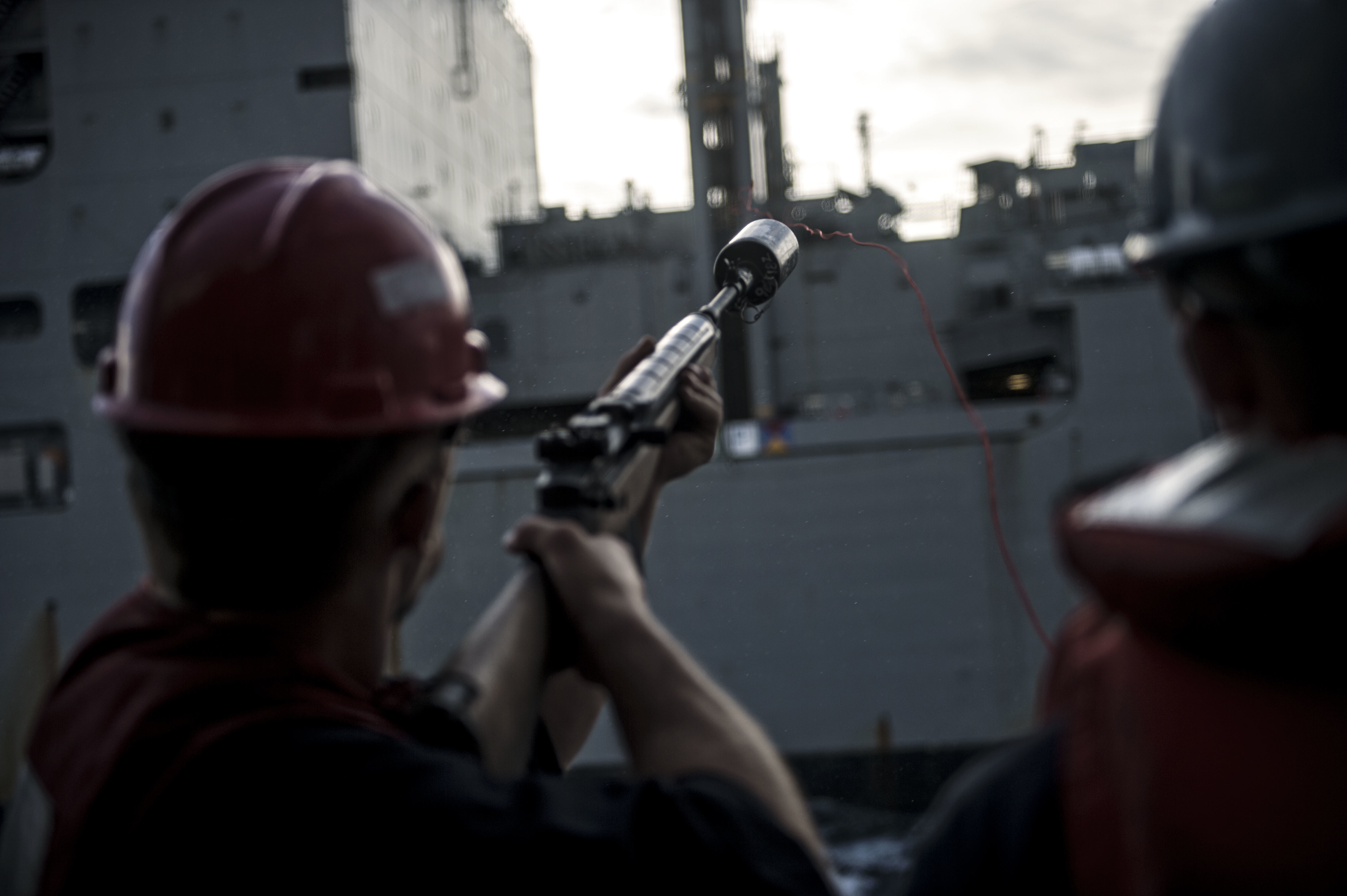 Gunner's Mate 2nd Class John N. Carter fires a shot line during a replenishment-at-sea with Military Sealift Command (MSC) dry cargo/ammunition ship USNS Matthew Perry (T-AKE 9) aboard the Ticonderoga-class guided-missile cruiser USS Chancellorsville (CG 62)