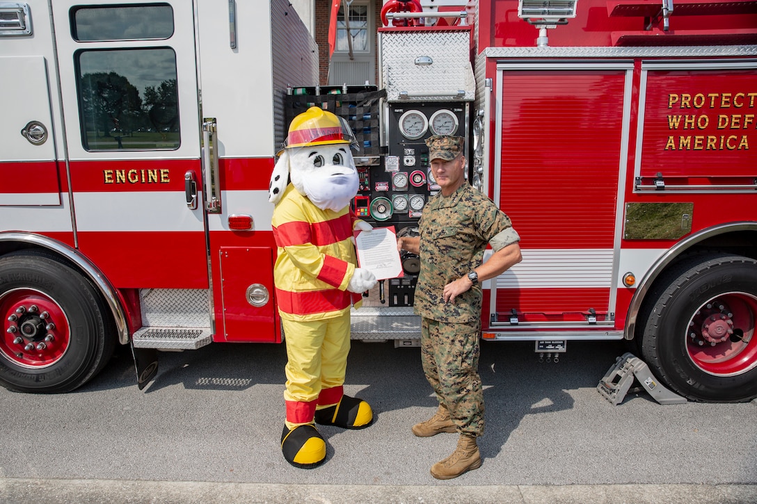 U.S. Marine Corps Maj. Gen. Julian D. Alford, commanding general, Marine Corps Installations East-Marine Corps Base Camp Lejeune, stands with the fire prevention proclamation with Sparky the fire dog on MCB Camp Lejeune, North Carolina, Oct. 6, 2020. This year’s fire prevention week teaches fire safety, precautions, and awareness while highlighting this year’s theme, "Serve Up Fire Safety in the Kitchen" running from Oct. 4-10. (U.S. Marine Corps photo by Lance Cpl. Christian Ayers)