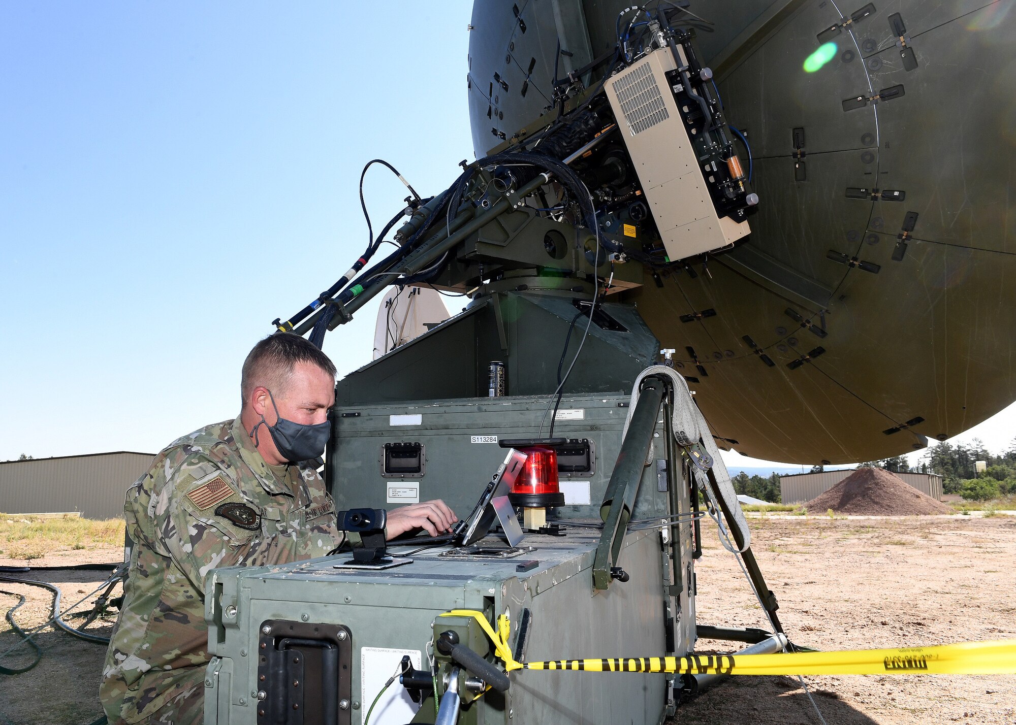 Master Sgt. Nathon Wheat, 379th Space Range Squadron, shifts focus from the Quadband Large Aperture Antenna to prepare a Video-Teleconference with those on telework status during the 379th SRS Field Training Exercise, Sept. 10-13, 2020, at the United States Air Force Academy's Field Engineering Readiness Laboratory, Colorado. (U.S. Air Force photo by Dennis Rogers)