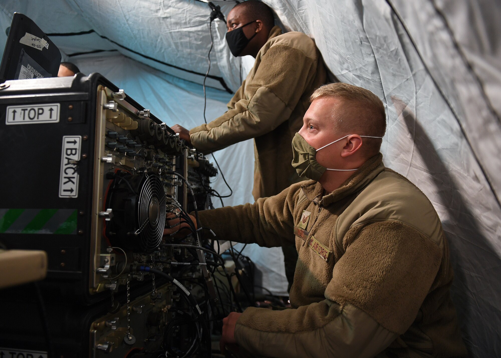 Tech. Sgt. Daniel Wood, 379th Space Range Squadron, checks physical connections to the modem on the Ground Multiband Terminal case while Master Sgt. Matthew Cleveland, 379th SRS, verifies the fix action prior to operations during the 379th SRS Field Training Exercise Sept. 10-13, 2020, at the United States Air Force Academy's Field Engineering Readiness Laboratory, Colorado. (U.S. Air Force photo by Dennis Rogers)