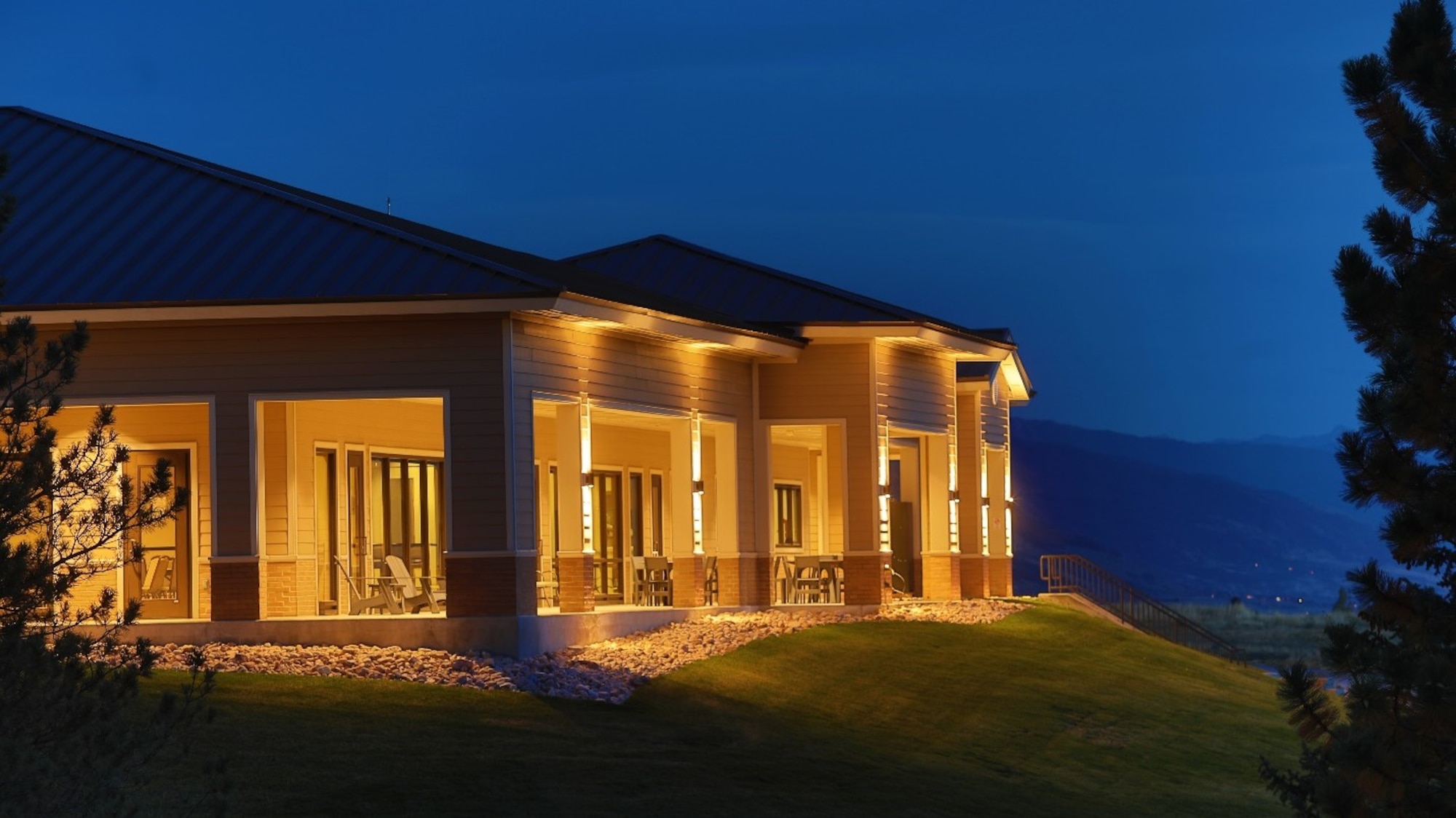 A profile of the clubhouse with its interior and exterior lights on at night.