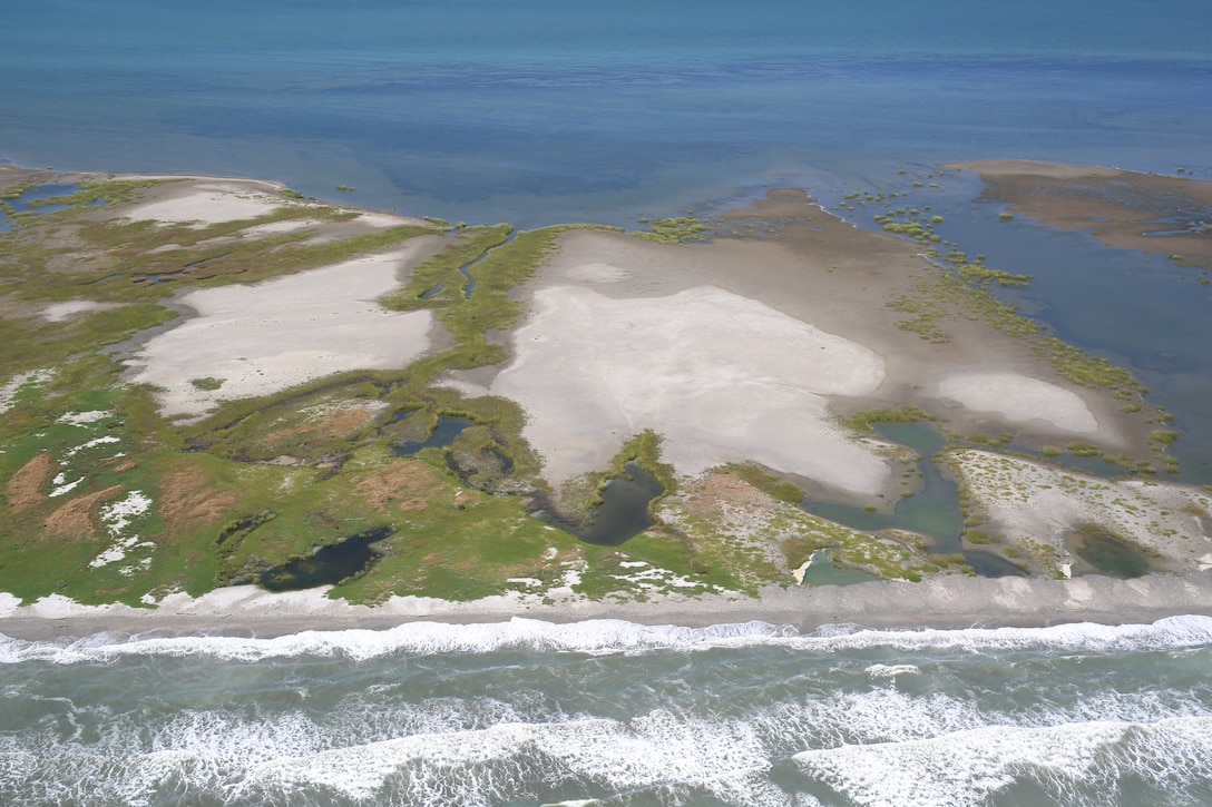 The state of Louisiana constructed two sand berms between 2010 and 2011 to protect the Chandeleur Islands as part of an emergency response plan to mitigate the effects of the Deepwater Horizon oil spill. Most of the sediment placed in the berms mimicked nearshore beneficial use of dredged material applications that are used for barrier island nourishment and restoration. A study found that sediment was transported onto existing island features or across the island into Chandeleur Sound. The build up and reinforcement of the island ensures its viability as wildlife habitat, making this an excellent example of working with natural processes to produce beneficial results. The effort to create the berms and evaluate them was a collaboration between multiple state and federal agencies, including the U.S. Army Corps of Engineers. (U.S. Geological Survey photo by Karen Morgan)