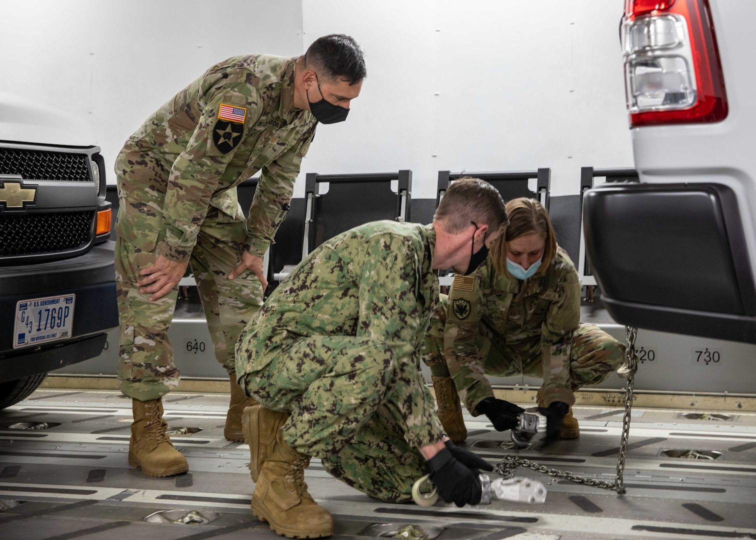 U.S. Air Force Master Sgt. Christina Anders, assigned to Joint Task Force Civil Support (JTF-CS), demonstrates how to tie down a fleet vehicle to U.S. Navy Lt. Cmdr. Stanley Worthington and U.S. Army Maj. Jason De Los Santos inside a C-17 Globemaster III trainer at Fort Lee, Va. during load training as part of Exercise KODA.
