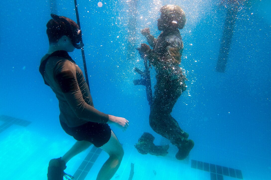 Two Coast Guardsmen train underwater.