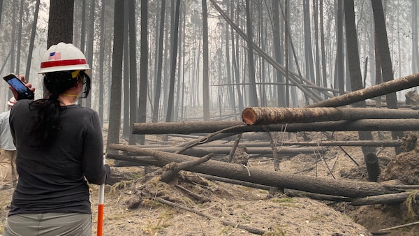 Erica Medley, a dam safety geologist with Portland District, U.S. Army Corps of Engineers, makes her way through thick smoke and fallen trees as she surveys damage on site at Blue River Dam Sept. 14. Medley joined a multi-disciplinary team of operations, engineering and dam safety personnel for a detailed inspection of the project just days after the Holiday Farm Fire burned through the area, impacting Blue River and nearby Cougar Dam.