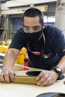 Pipefitter Apprentice Tyler Winner is cutting holes into a Garlock gasket to ensure proper fitting on the lube oil pipe. This work was in support of the USS John Paul Jones (DDG 53) lube oil job.