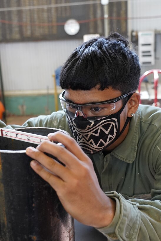 Pipefitter Apprentice Chris Kau is fitting up a measurement for a Garlock gasket. This work was in support of the USS John Paul Jones (DDG 53) lube oil job.