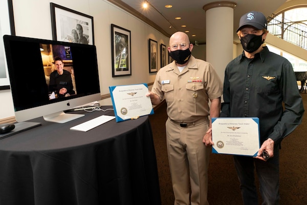 Vice Adm. DeWolfe H. Miller III (c), Commander, U.S. Naval Air Forces, presents Honorary Naval Aviator designations to actor Tom Cruise (l), and film producer Jerry Bruckheimer (r), in recognition of their significant and continuous support of Naval Aviation throughout the production of films Top Gun and Top Gun: Maverick.