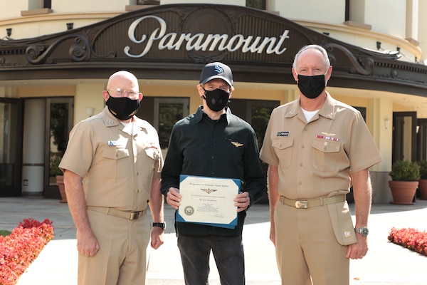 Vice Adm. DeWolfe H. Miller III (l), Commander, U.S. Naval Air Forces, and Rear Adm. Kenneth R. Whitesell (r) present the Honorary Naval Aviator designation to Jerry Bruckheimer (c), producer of Top Gun and Top Gun: Maverick, at Paramount studios in recognition of his significant and continuous support of Naval Aviation. Bruckheimer is the 35th Honorary Naval Aviator.