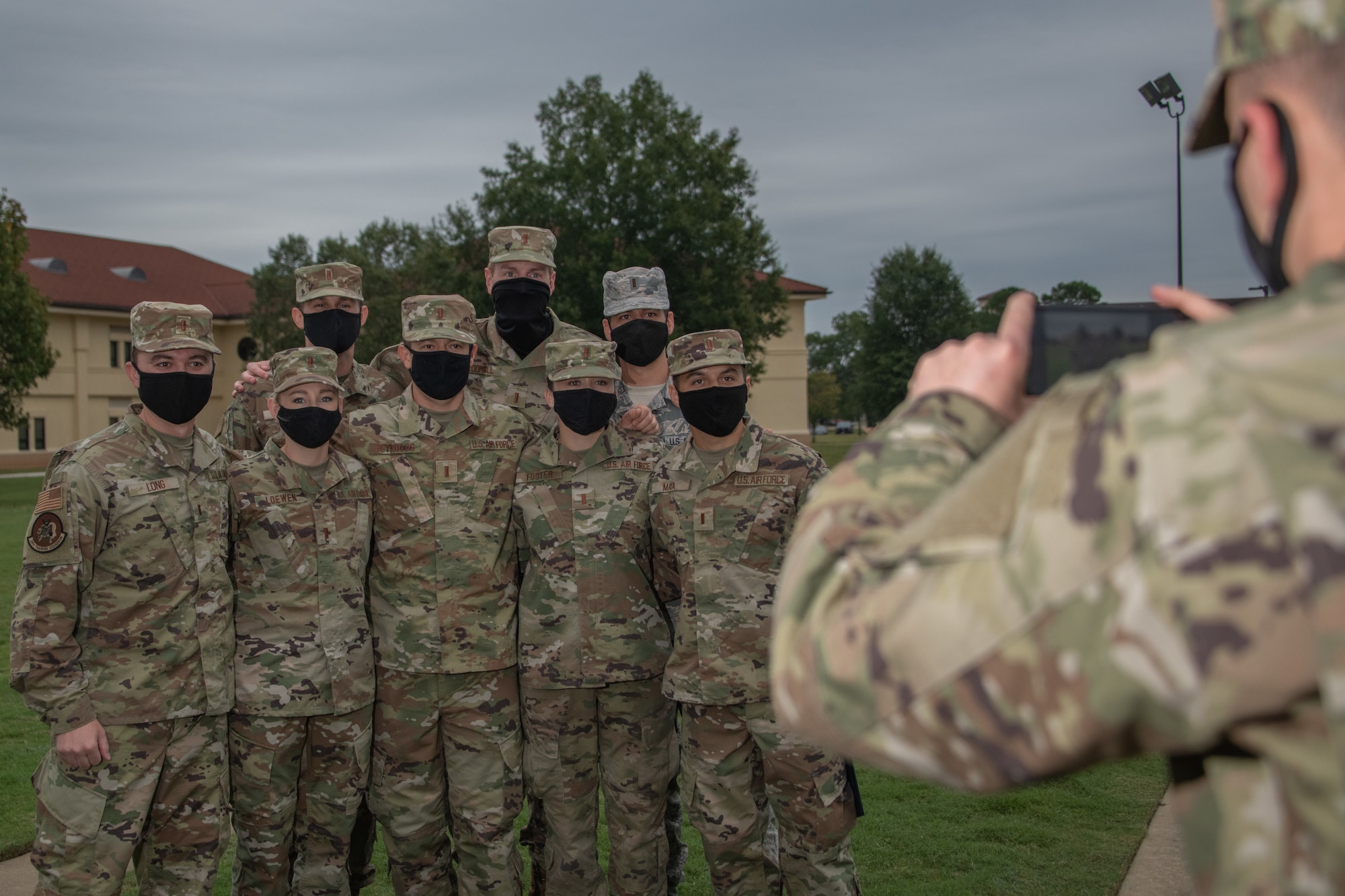 An Officer Training School graduate takes a photo of his classmates after their parade ceremony