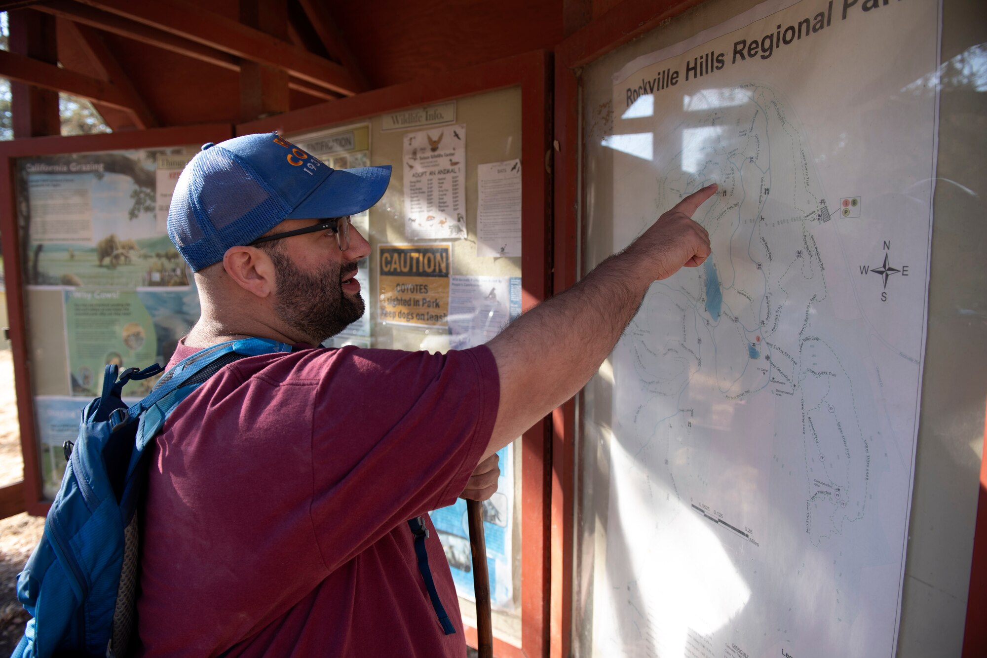 A man is touching a map near the beginning of a trail.