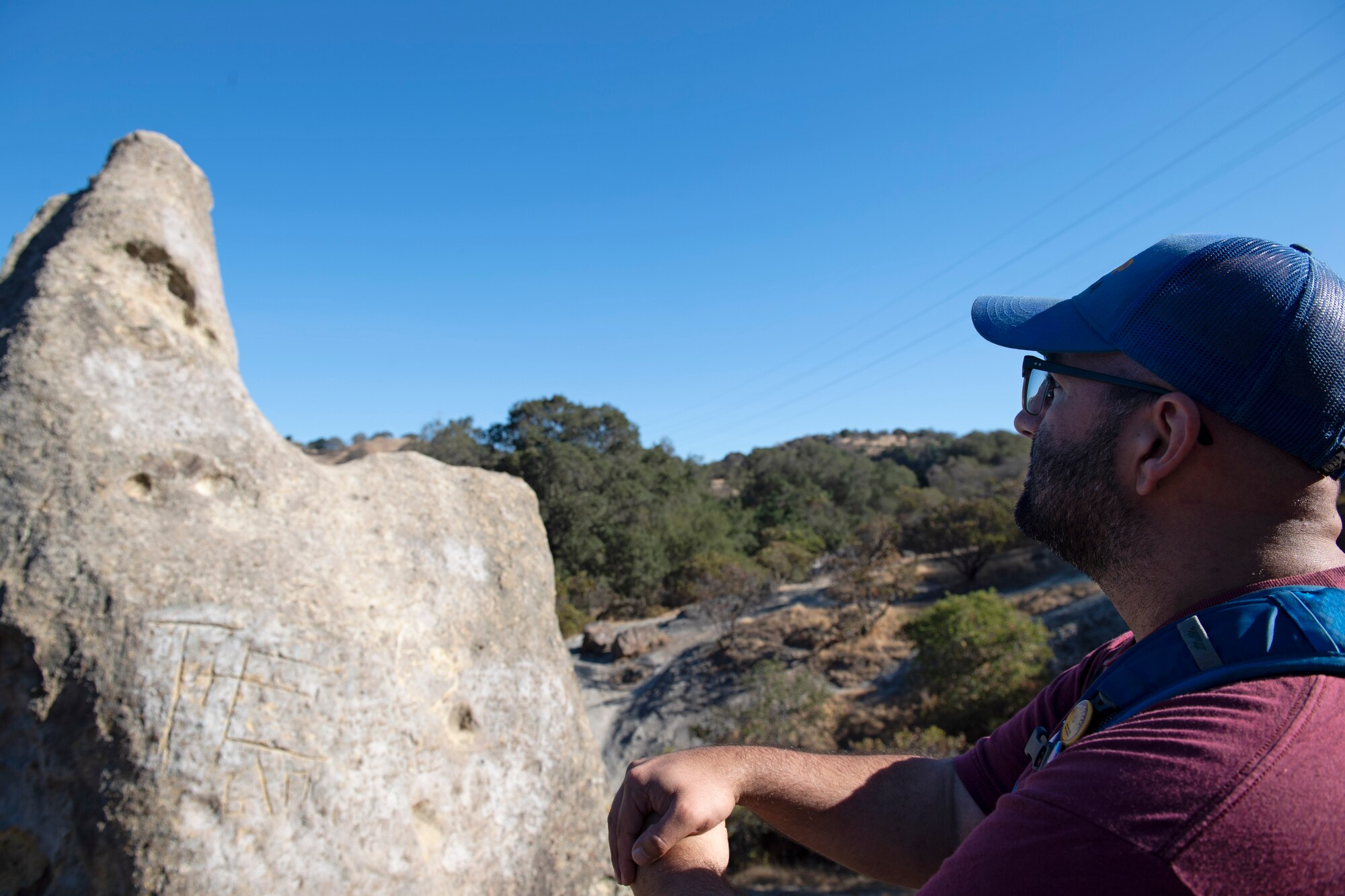 A man stares off into the woods during a hike.