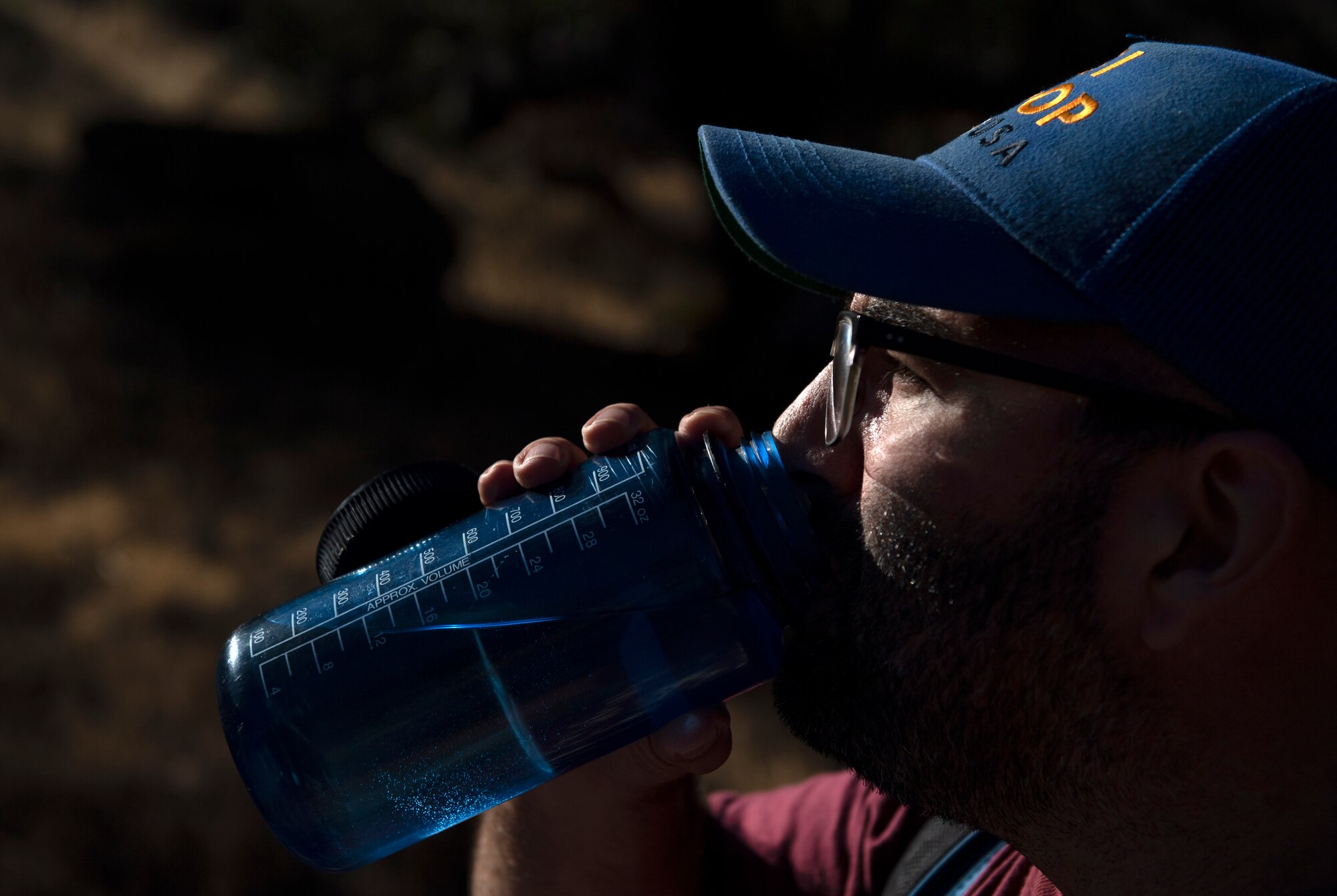 A man takes a drink of water during a hike.