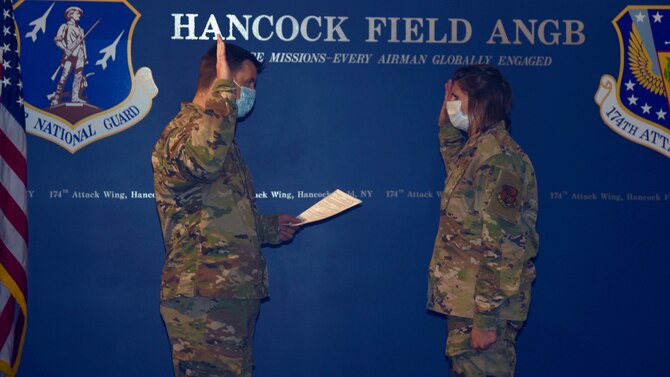 Capt. Devin Will (left) reads the Oath of Enlistment to Staff Sgt. Megan Fowler during a re-enlistment ceremony at Hancock Field Air National Guard Base September 28