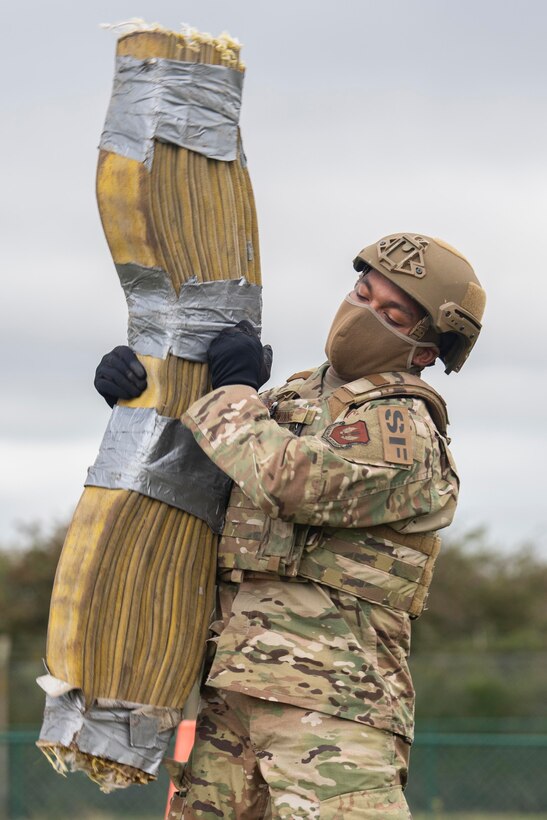 U.S. Air Force Airman Johnnie Swinnie, 100th Security Forces Squadron response force member, picks up a weight made of cut firehoses during the fire muster competition at Royal Air Force Mildenhall, England, Oct. 8, 2020. The fire muster was held to raise fire prevention awareness. (U.S. Air Force photo by Airman 1st Class Joseph Barron)