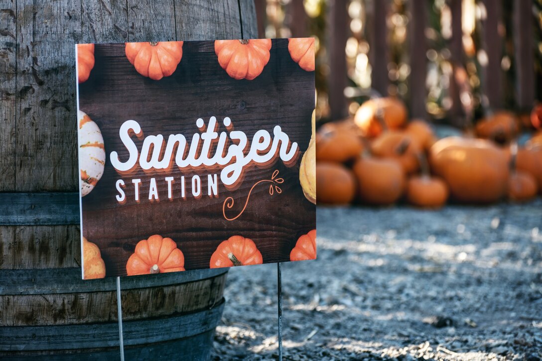 A sign in a pumpkin patch promotes a Sanitizer Station
