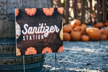 A sign in a pumpkin patch promotes a Sanitizer Station