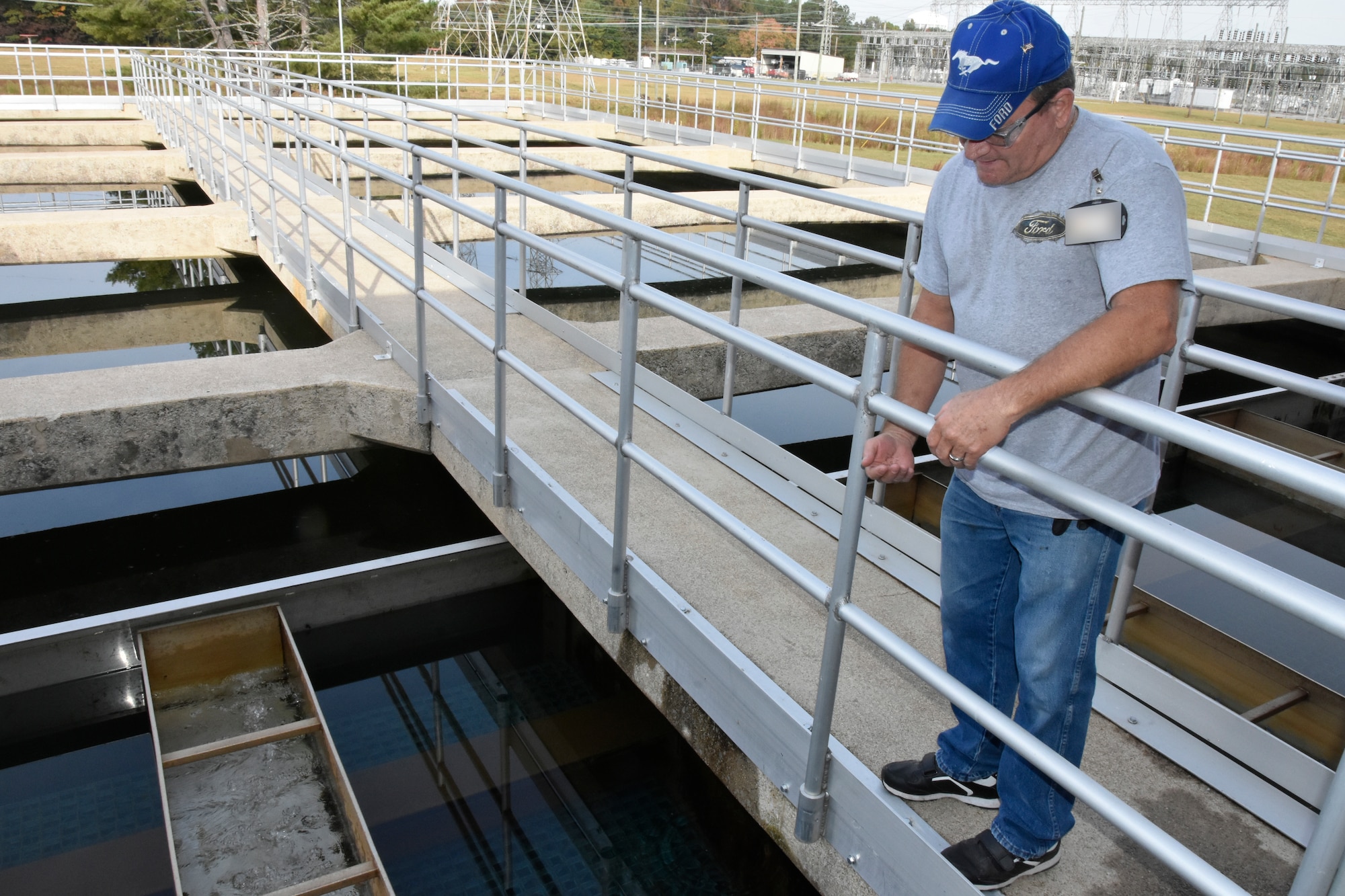 Frankie Hill, lead operator at the Arnold Air Force Base Water Treatment Plant, discusses the new tube settlers added as part of multimillion-dollar renovation project at the plant Oct. 8, 2020. Theses tube settlers, one of which is pictured at left, remove an increased amount of solids from water as it is treated which increases the efficiency of plant filters. Behind Hill are sedimentation basins used to remove particles from water coming into the plant for treatment. Each of these basins received a protective coating during the recently-completed renovations. (U.S. Air Force photo by Bradley Hicks) (This photo has been altered by obscuring badges for security purposes)