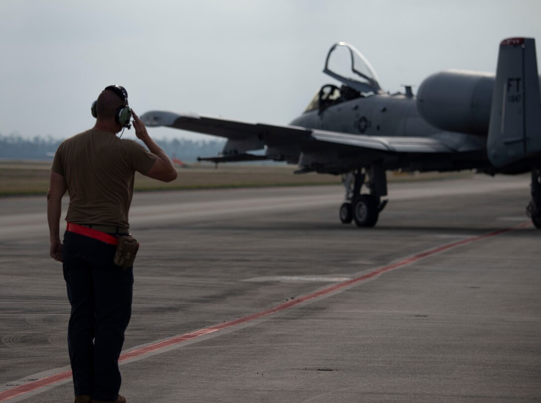 man salutes A-10 in background