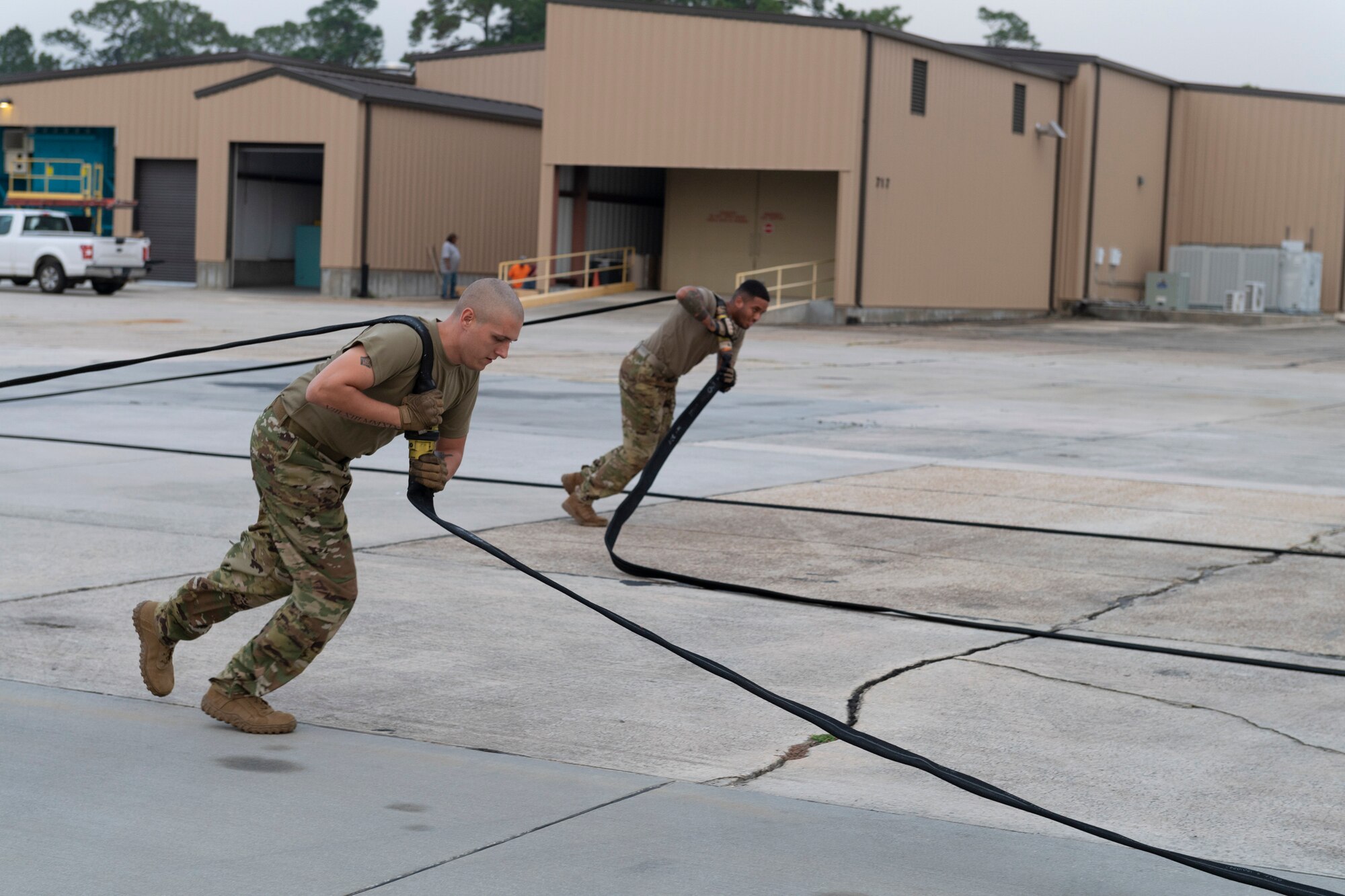 A photo of two airmen pulling fuel hoses.