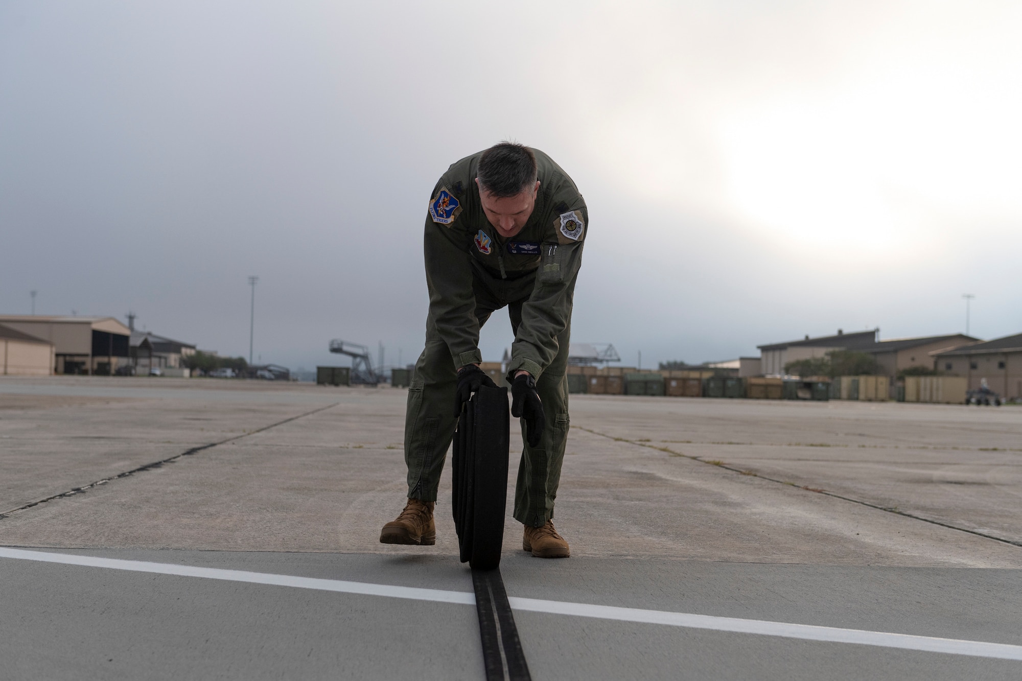 A photo of an airman rolling up a fuel hose.