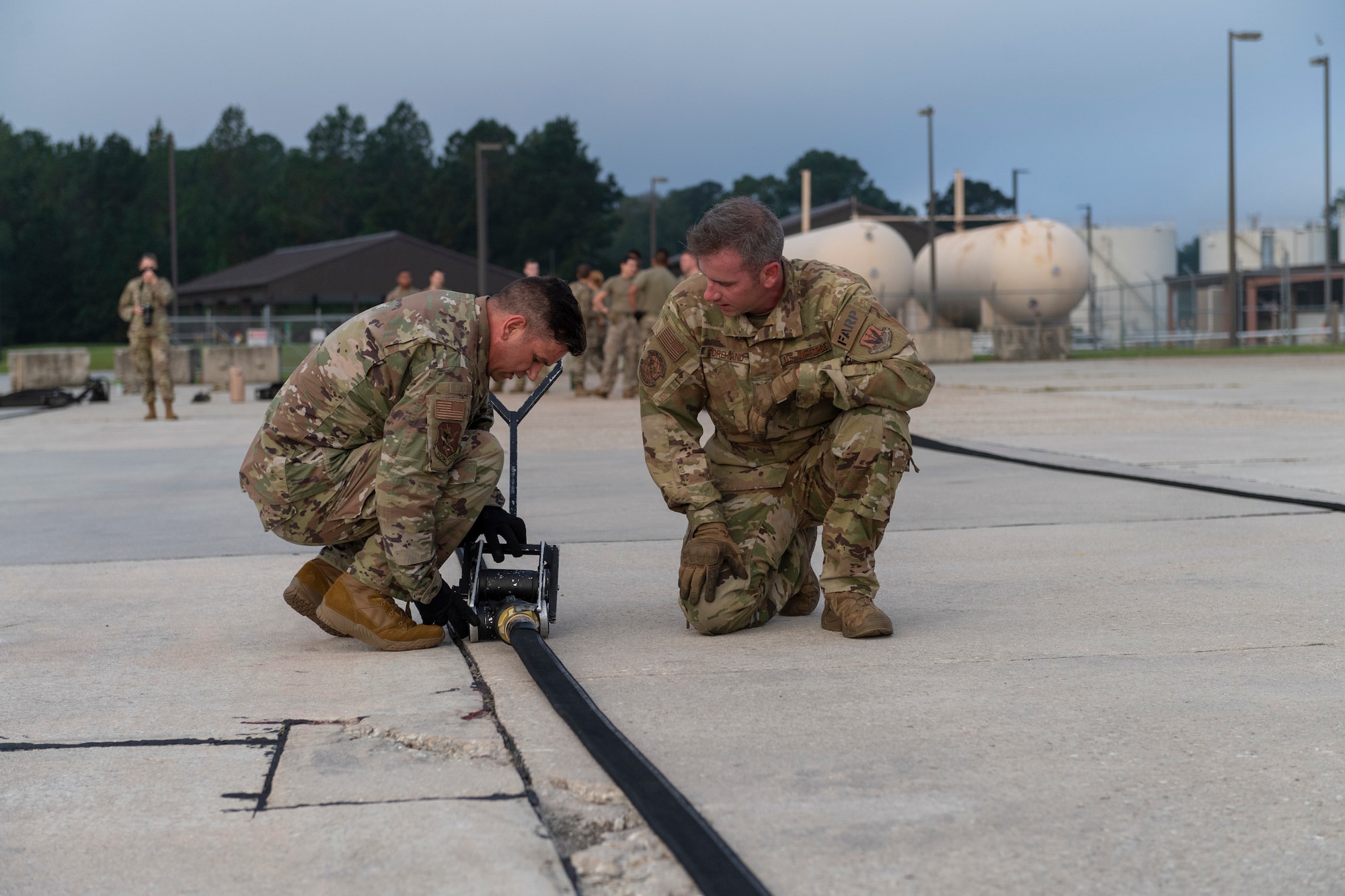 A photo of two airmen attaching a squeegee to a fuel hose.