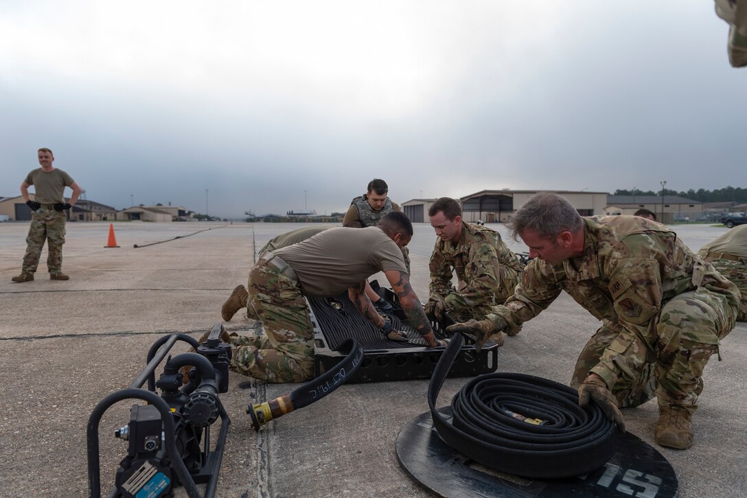 A photo of airmen unraveling a fuel hose into a basket.