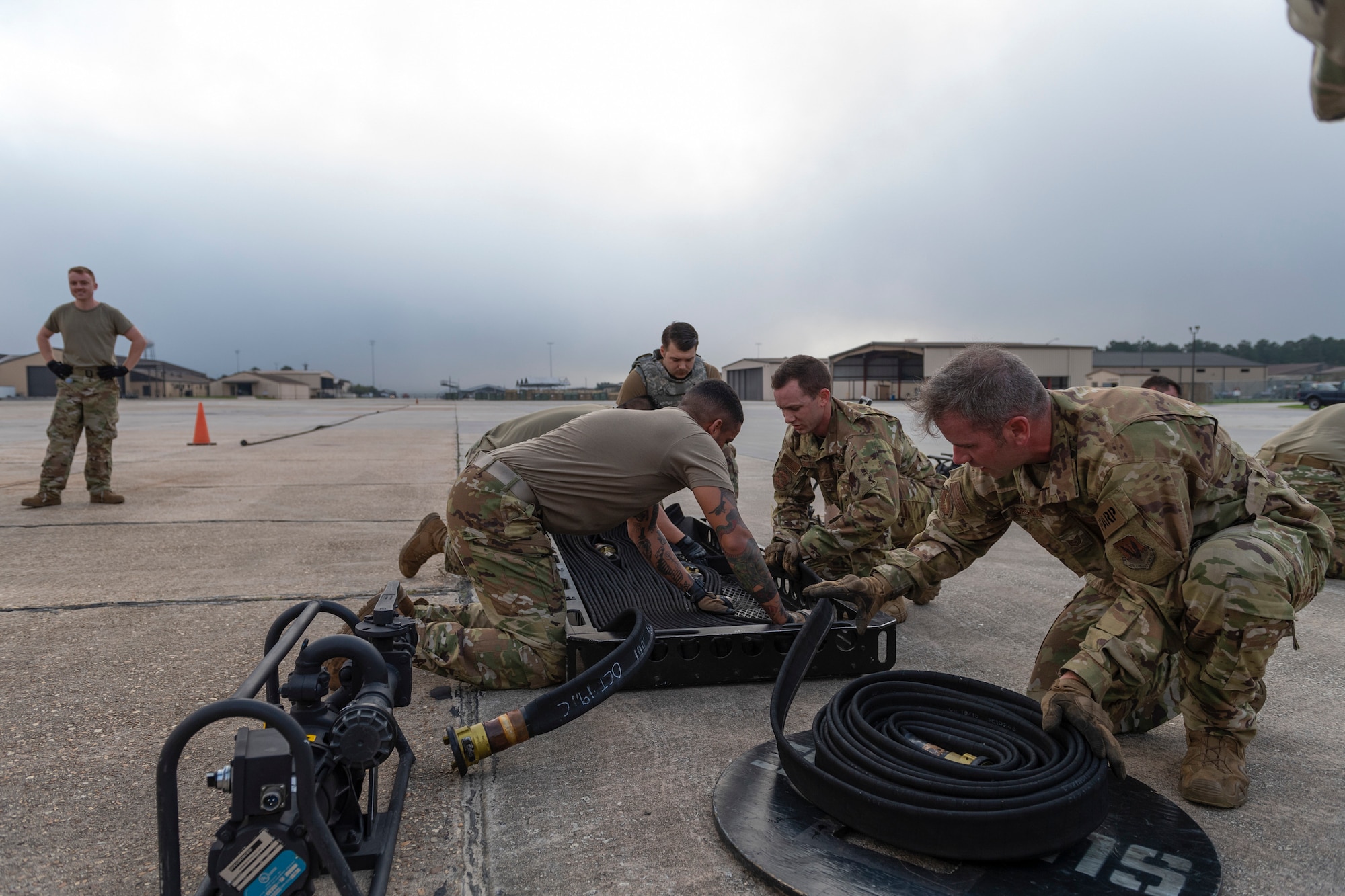 A photo of airmen unraveling a fuel hose into a basket.