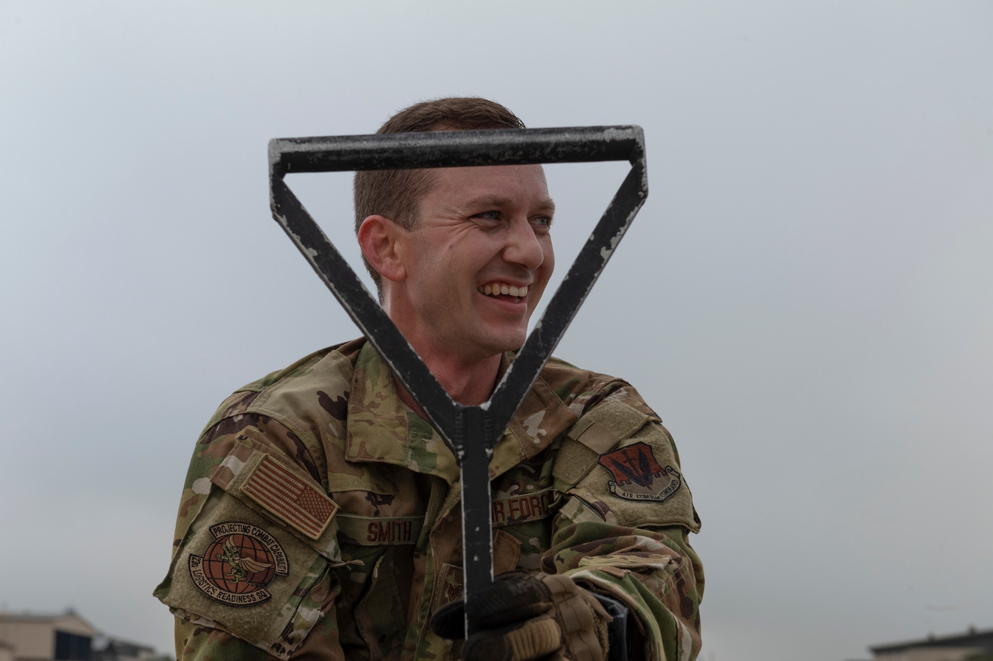 A photo of an airman smiling, holding a hose squeegee.