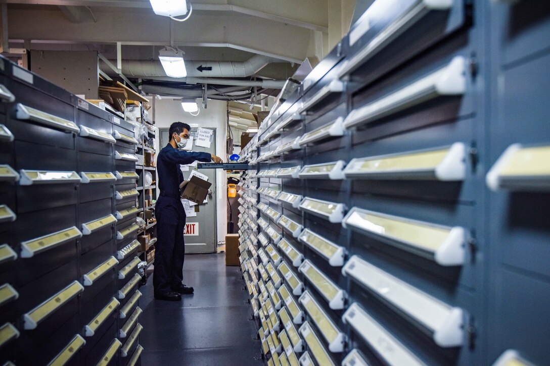 A sailor works in an office aboard a military ship.