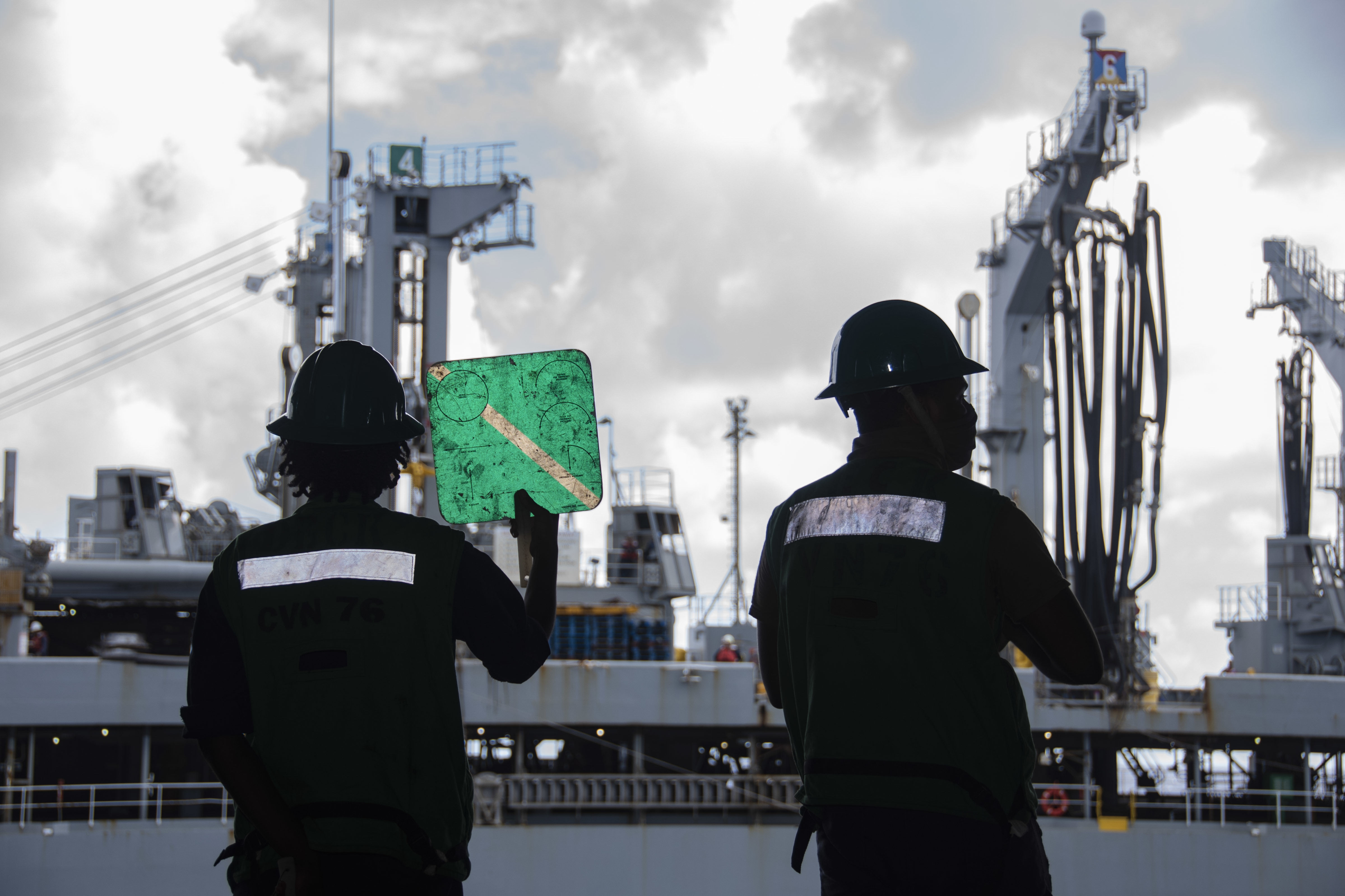 Sailors signal to fleet replenishment oiler USNS Pecos (T-AO 197) from the hangar bay of the Navy�s only forward-deployed aircraft carrier USS Ronald Reagan (CVN 76) during a replenishment-at-sea.