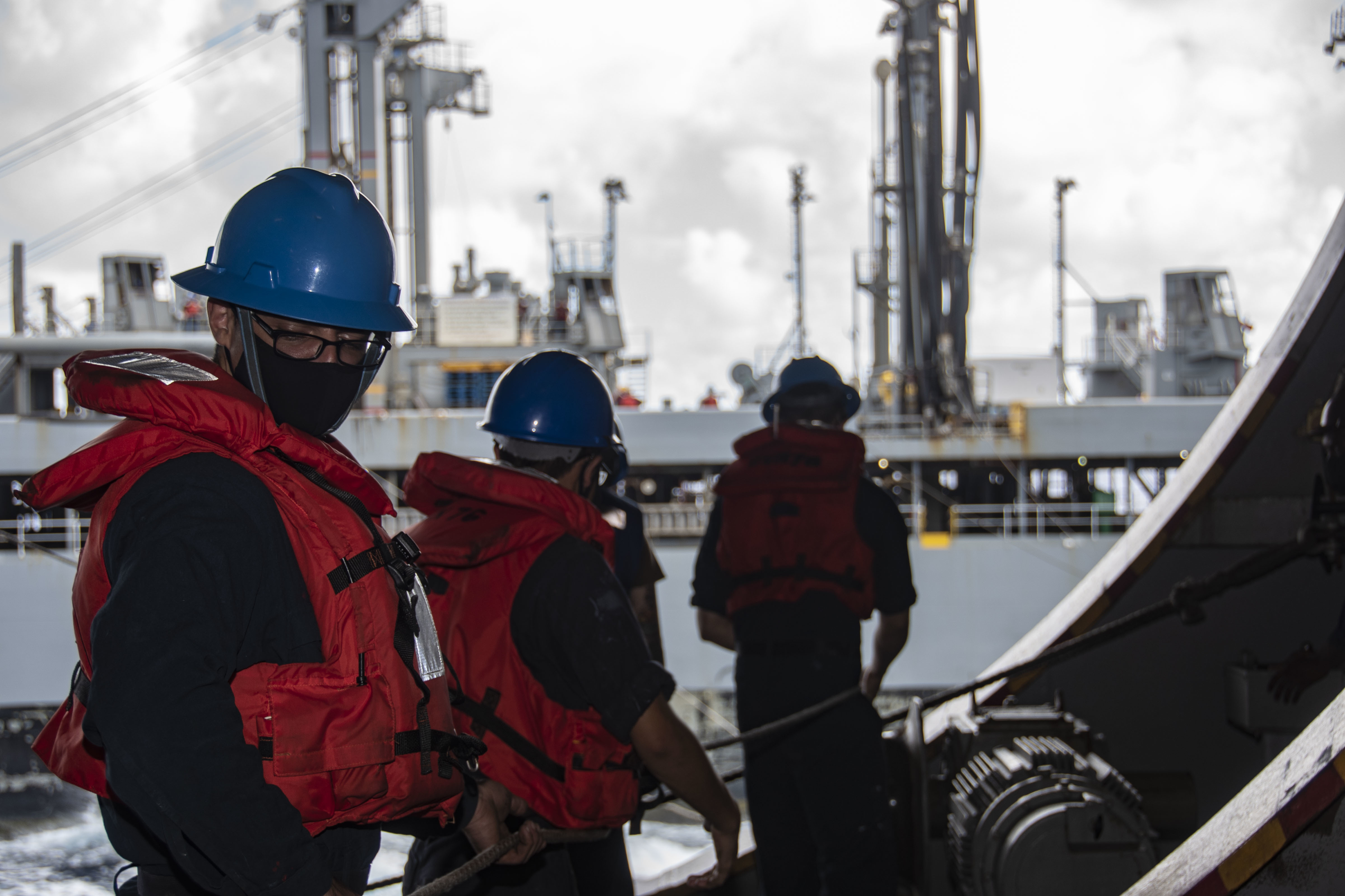 Sailors handle line during a replenishment-at-sea with fleet replenishment oiler USNS Pecos (T-AO 197) in the hangar bay of the Navy�s only forward-deployed aircraft carrier USS Ronald Reagan (CVN 76).