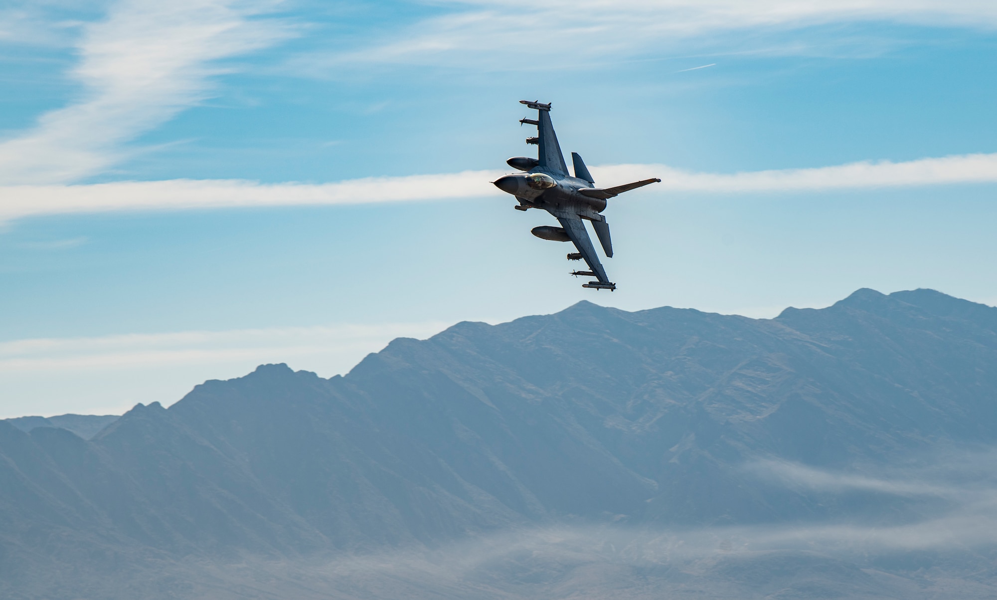 F-16 flies over mountain.