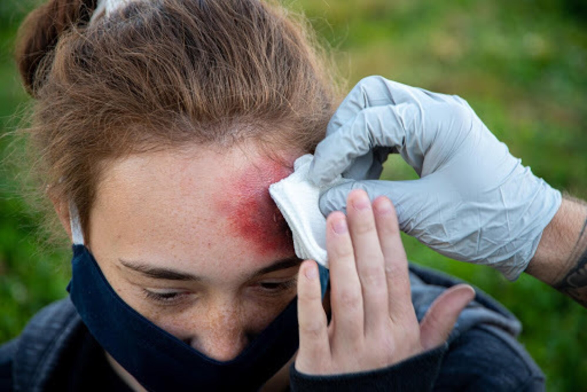 Image of an Air Force medic applying a bandage to a simulated wound outside of the base theater.