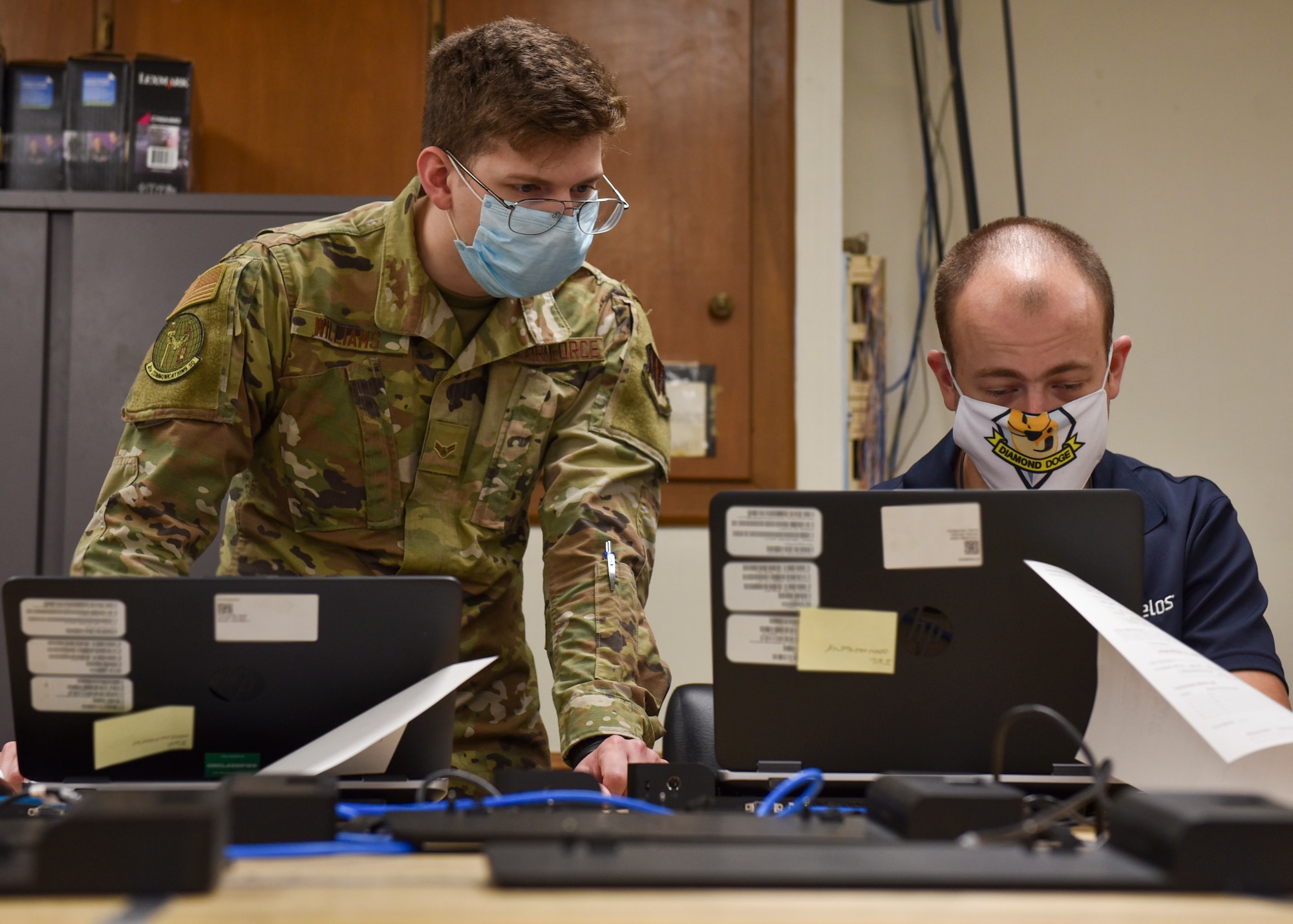 Airman 1st Class Tristan Williams, 4th Communications Squadron, communications focal point client systems technician (left), and Timothy Leineke, 4CS CFP computer support technician, explore ways to remotely add computers to the domain at Seymour Johnson Air Force Base, North Carolina, Sept. 22, 2020.