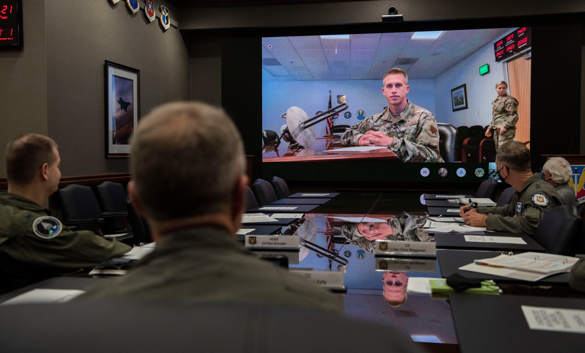 ACC 4 Star General sitting at table with screen in front of him