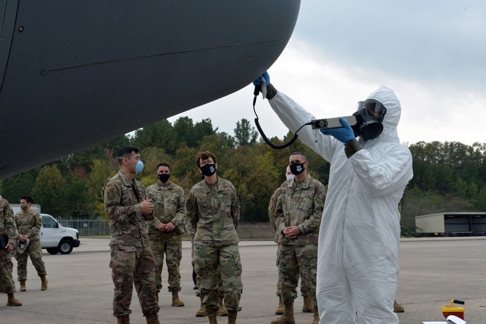 Man in Hazmat suit simulates decon procedures on C-130J with commander looking on