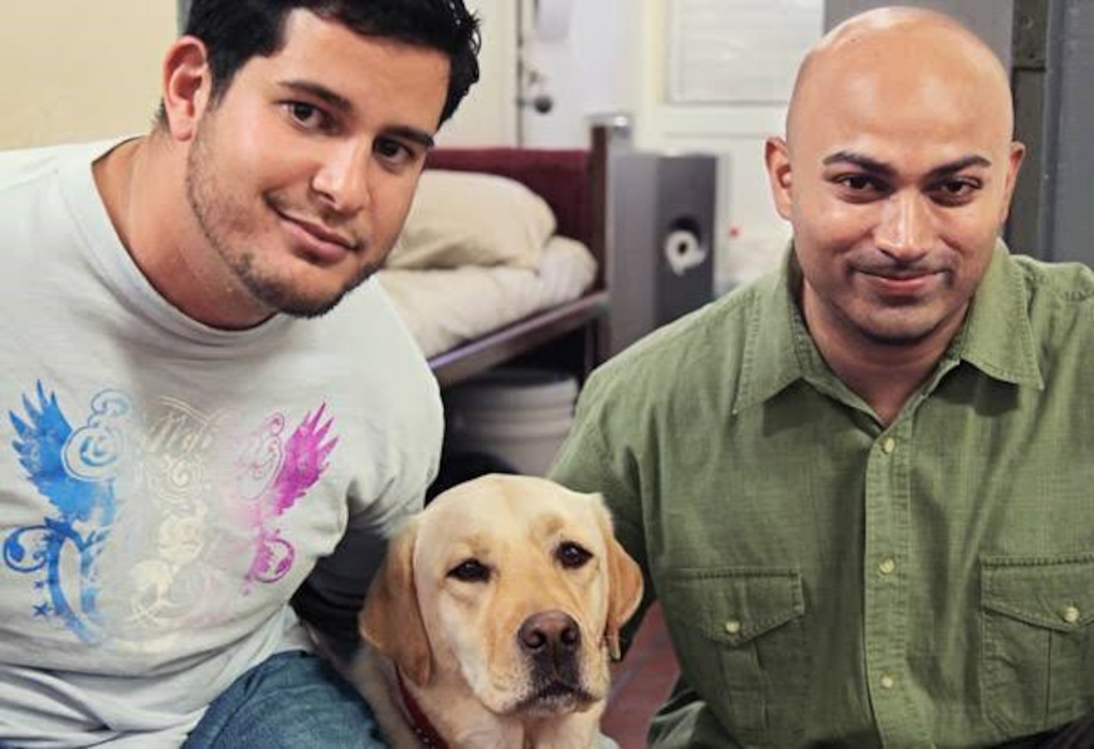 William Pagan, a Defense Logistics Agency forward logistics specialist, left, poses beside his former service dog, a yellow lab named Oprah, and her trainer Vijay Ramroop.