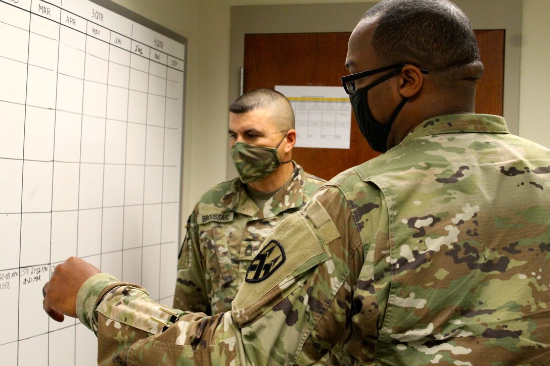 Lt. Col. Samuel Bates (right), a G-7 officer at the 377th Theater Sustainment Command, discusses training with Master Sgt. Richard Broussard at the headquarters building in Belle Chasse, La., Oct. 20, 2020.