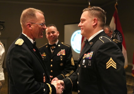 The Adjutant General of the Missouri National Guard, Brig. Gen. Levon Cumpton, recognizes Sgt. Joshua Roth during the National Guard Birthday Ball in December 2019, as the State Command Sergeant Major, Command Sgt. Maj. Kannon John looks on.