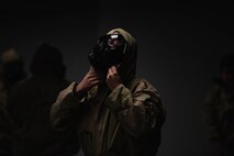 Airman adjusts hood of MOPP gear.