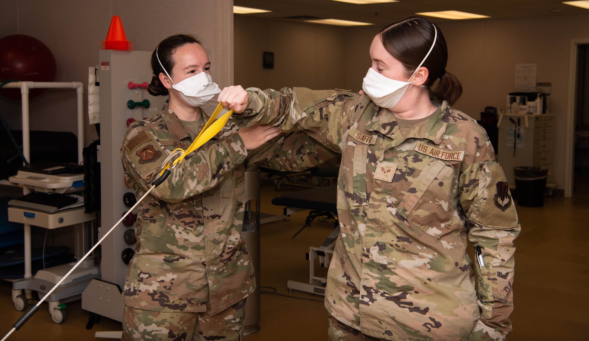 U.S. Air Force Capt. Jenna Boyd assists an Airman with an external shoulder rotation exercise.