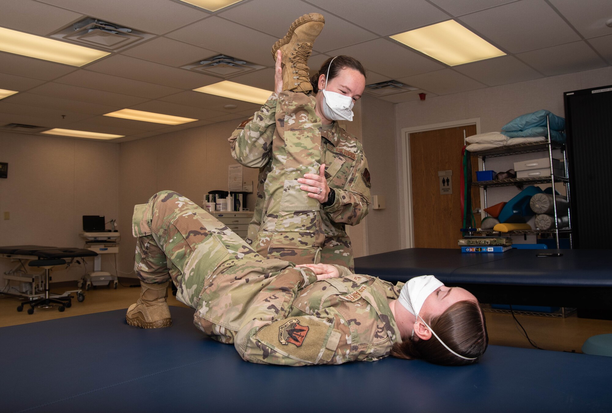 U.S. Air Force Capt. Jenna Boyd assists an Airman with hamstring stretches.