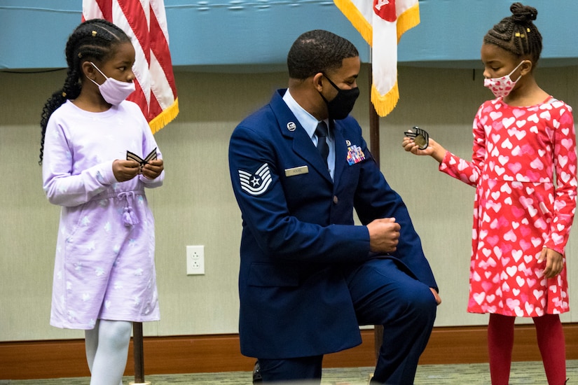 The two daughters of Eldridge Rouse pin their fathers rank on as he is promoted from Staff Sgt. to Tech. Sgt. in U.S. Army Central headquarters on Shaw Air Force Base, S.C., Oct. 7, 2020. The Rouse family were together to attend Tyris' retirement ceremony which turned out to be a surprise reunion for Eldridge and the family. (U.S. Army photo by Pfc. Keon Horton)