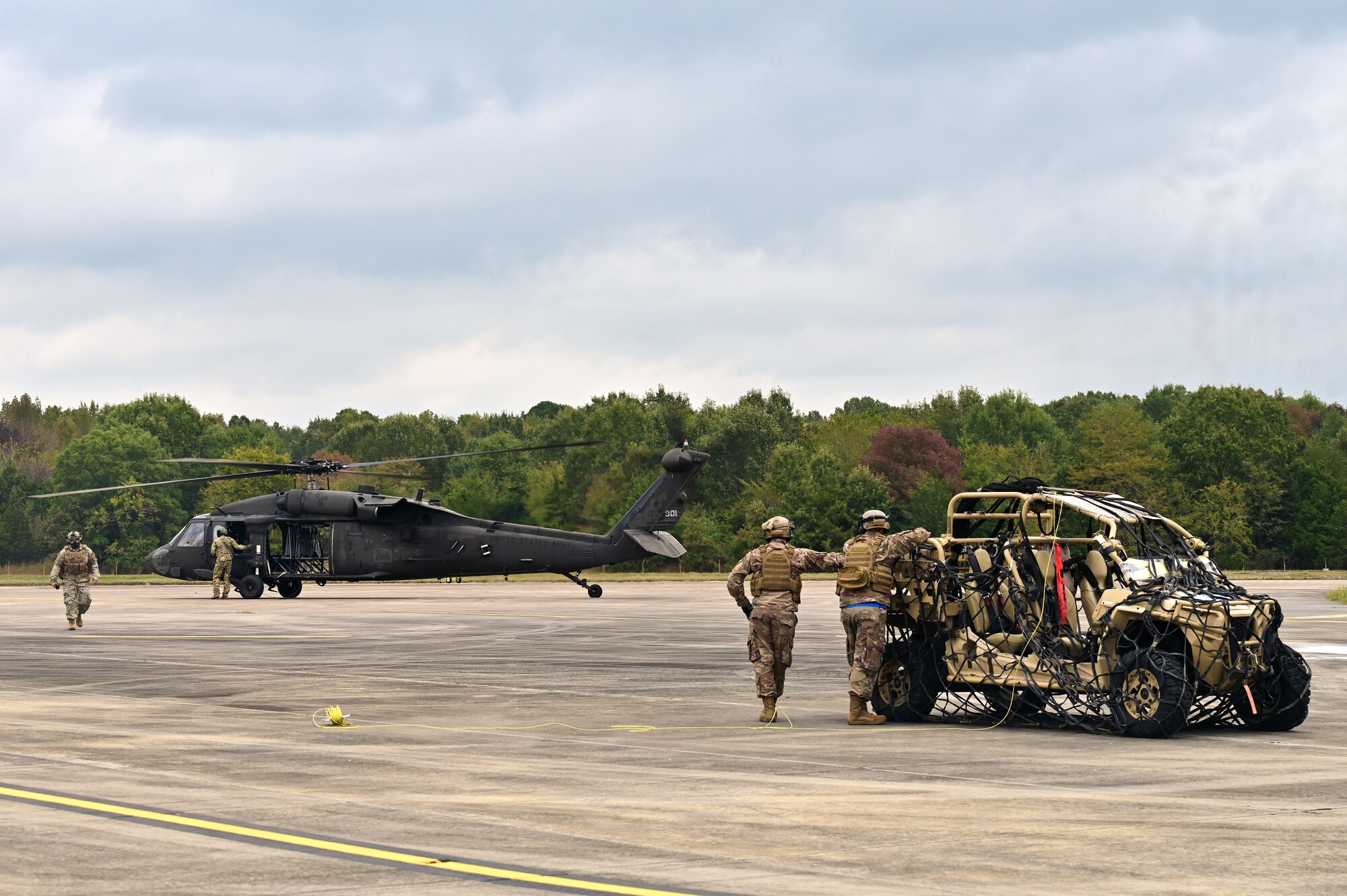 A group of Airmen prepare an off-road vehicle to be connected to a helicopter.