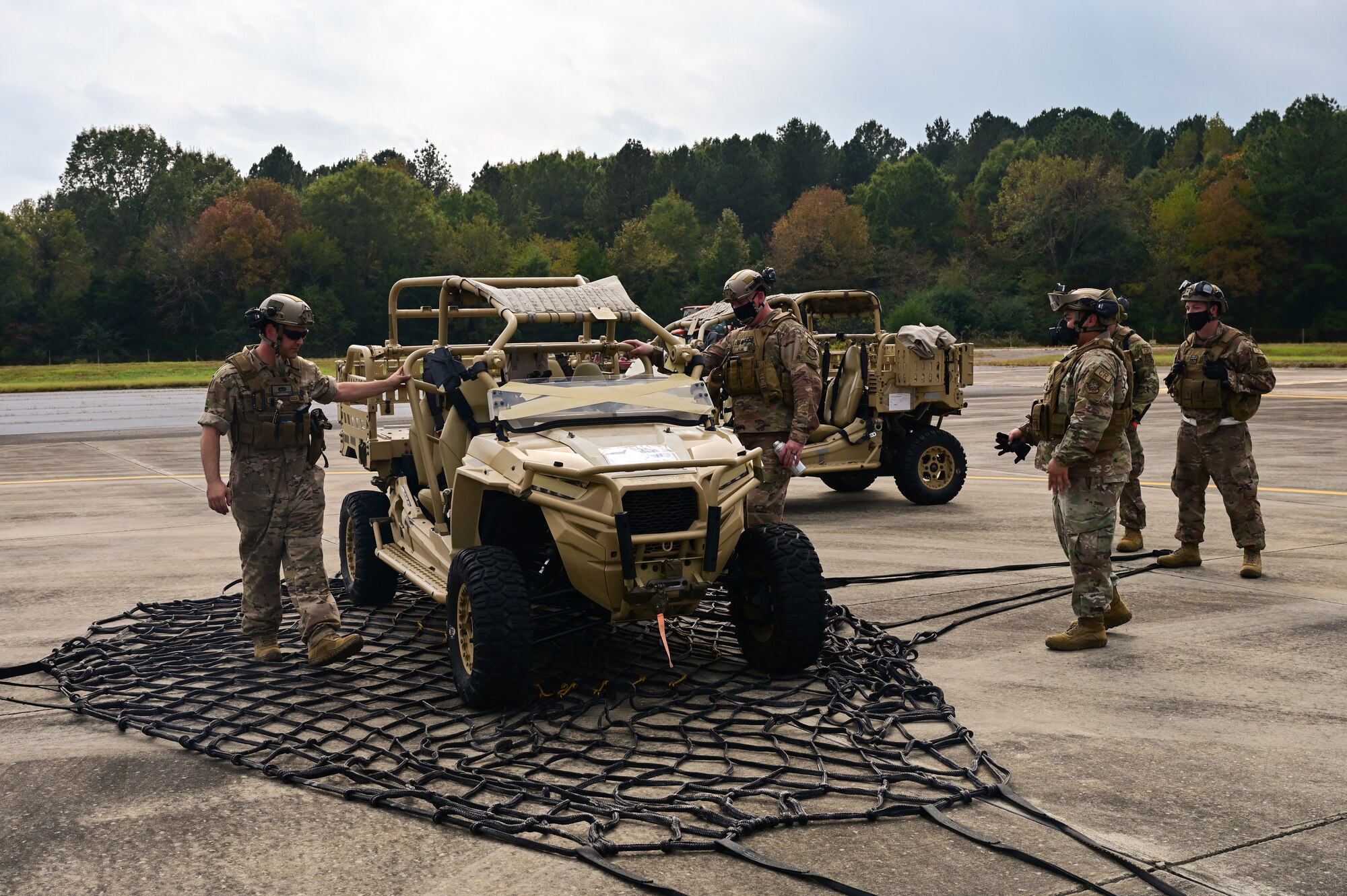 4 Airmen inspect an offroad vehicle that has just been released form a net.