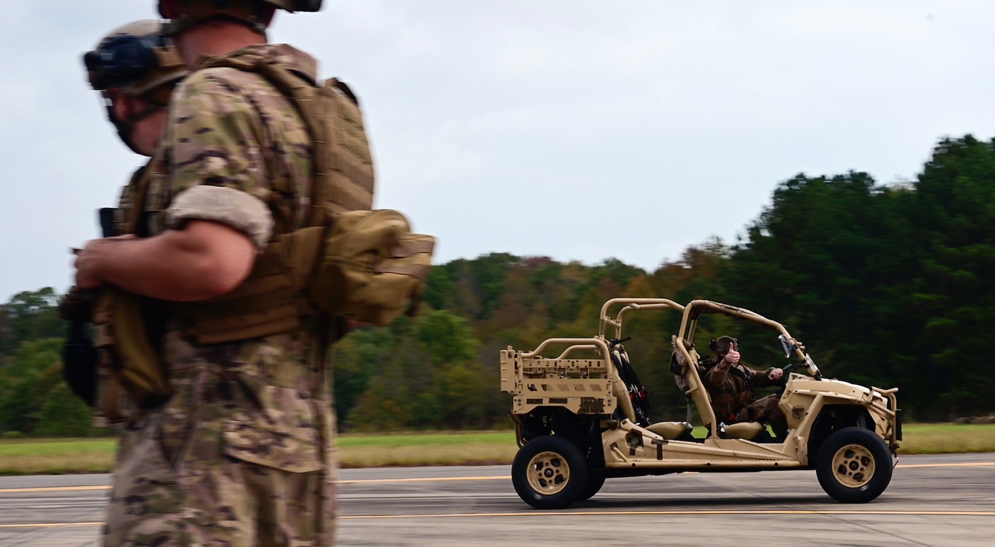 An Airman drives a offroad vehicle on a concrete path.