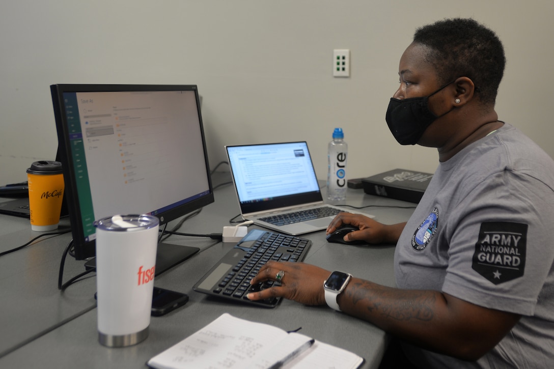 A woman wearing a mask works on a computer.
